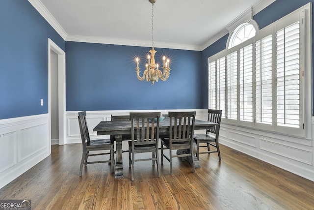 dining room with ornamental molding, wood finished floors, a wainscoted wall, and a chandelier