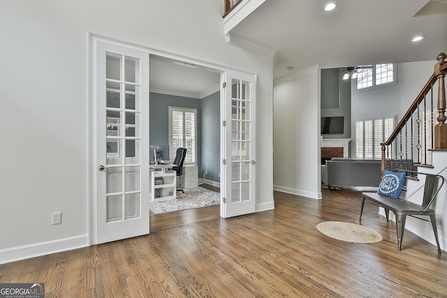 interior space featuring wood finished floors, baseboards, ornamental molding, ceiling fan, and french doors