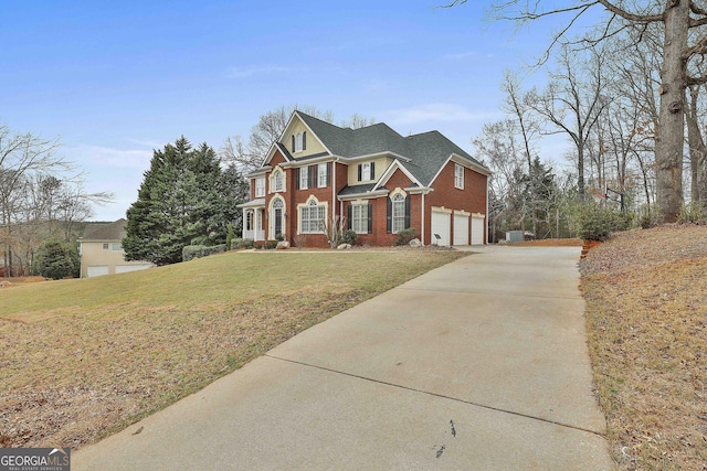 view of front facade with a front yard, brick siding, an attached garage, and driveway