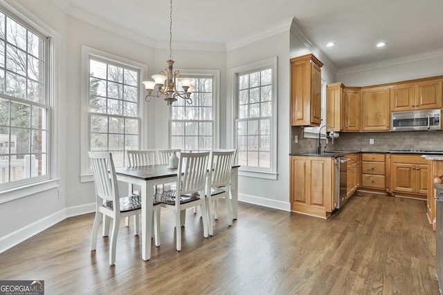 dining space featuring a chandelier, dark wood finished floors, crown molding, and baseboards