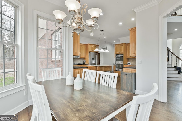 dining room featuring stairs, crown molding, an inviting chandelier, and wood finished floors