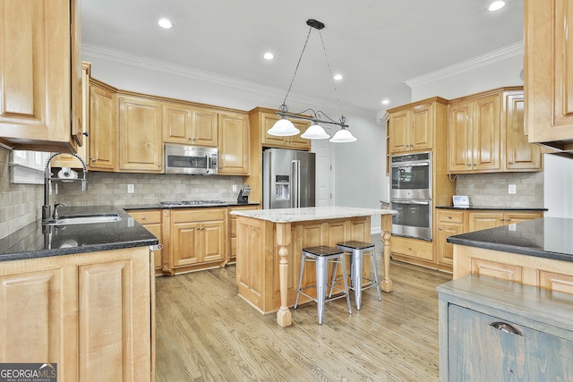 kitchen with ornamental molding, a sink, a kitchen island, appliances with stainless steel finishes, and light wood finished floors