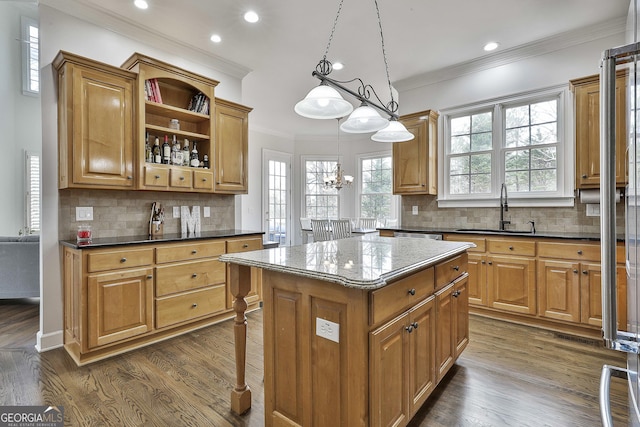 kitchen with dark wood finished floors, ornamental molding, a kitchen island, and a sink