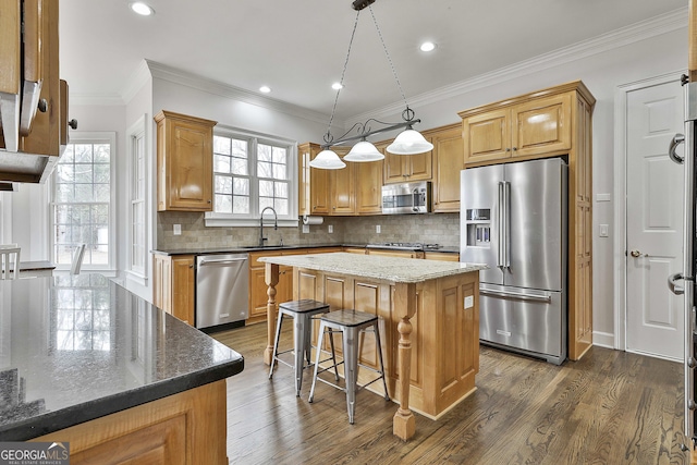 kitchen with dark stone countertops, dark wood-style floors, a kitchen island, a sink, and stainless steel appliances