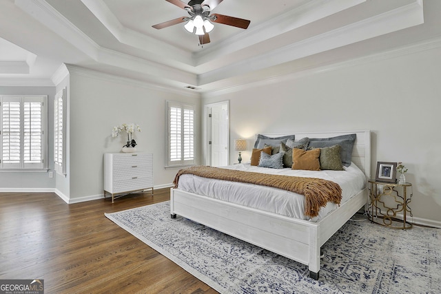 bedroom featuring visible vents, crown molding, baseboards, wood finished floors, and a raised ceiling