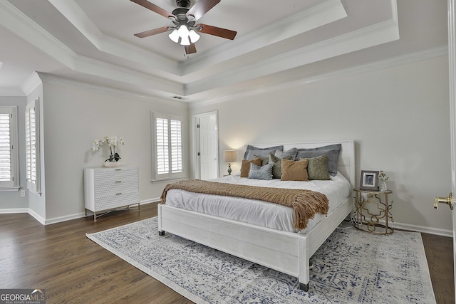 bedroom with a raised ceiling, wood finished floors, and baseboards