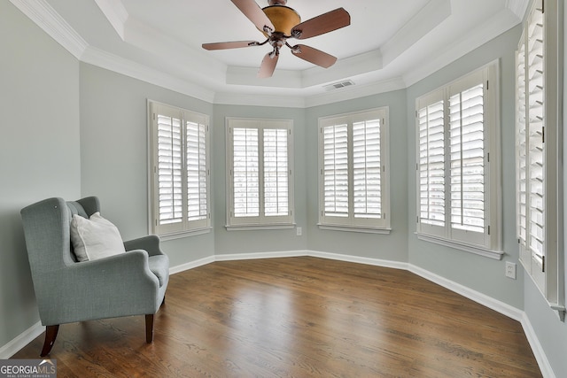 sitting room with visible vents, ornamental molding, a tray ceiling, wood finished floors, and baseboards