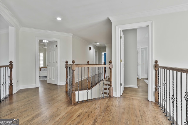 hall with baseboards, an upstairs landing, wood finished floors, and crown molding