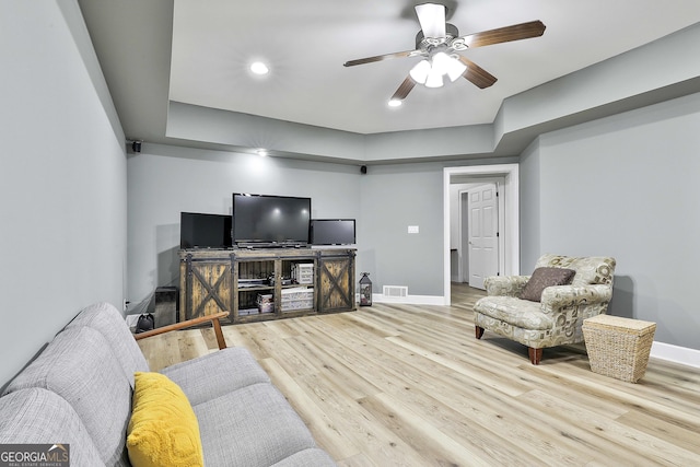 living area with visible vents, baseboards, wood finished floors, and a ceiling fan