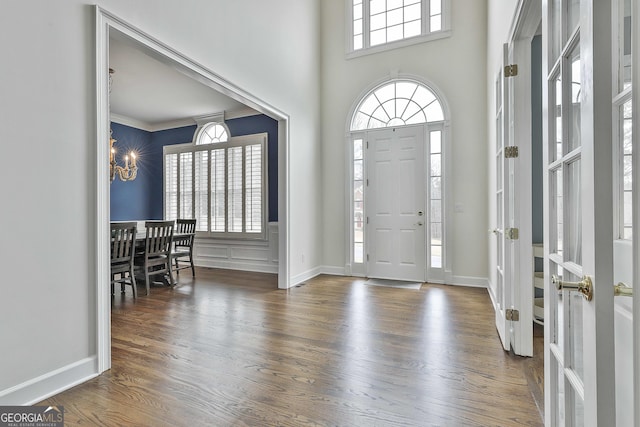 entryway featuring baseboards, an inviting chandelier, wood finished floors, and crown molding