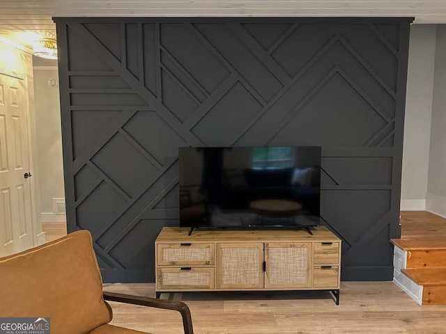 interior space featuring a decorative wall, wood finished floors, and baseboards