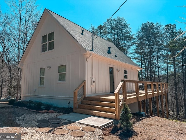 exterior space with a deck and roof with shingles