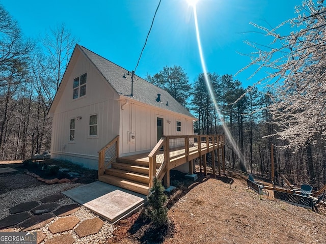 rear view of house with a wooden deck and roof with shingles