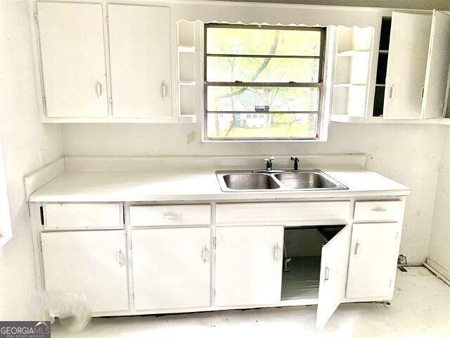 kitchen featuring white cabinetry, light countertops, and a sink