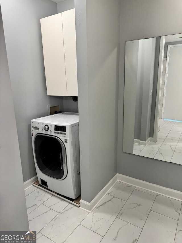 washroom with baseboards, cabinet space, marble finish floor, and washer / dryer