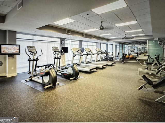 exercise room featuring a paneled ceiling, visible vents, and expansive windows