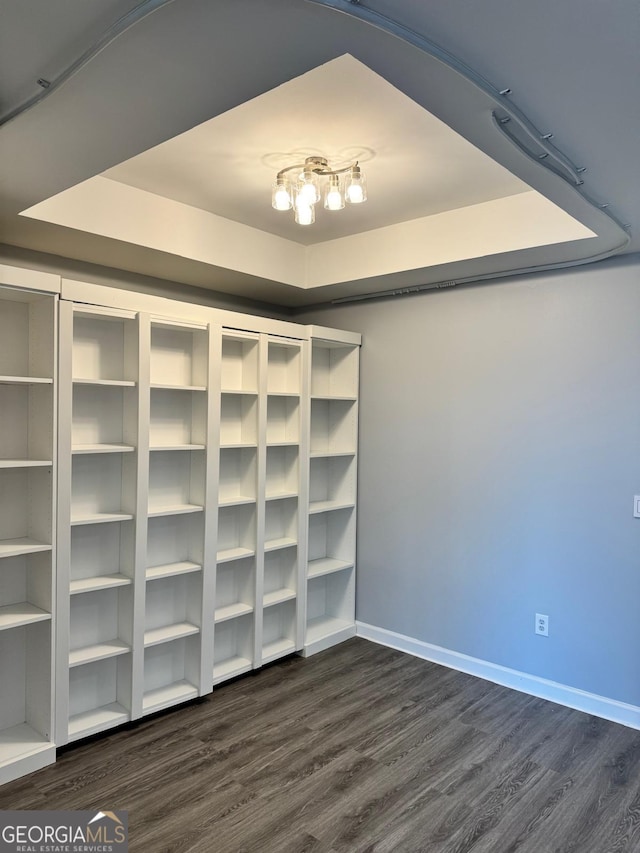 interior space with a tray ceiling and dark wood-style flooring