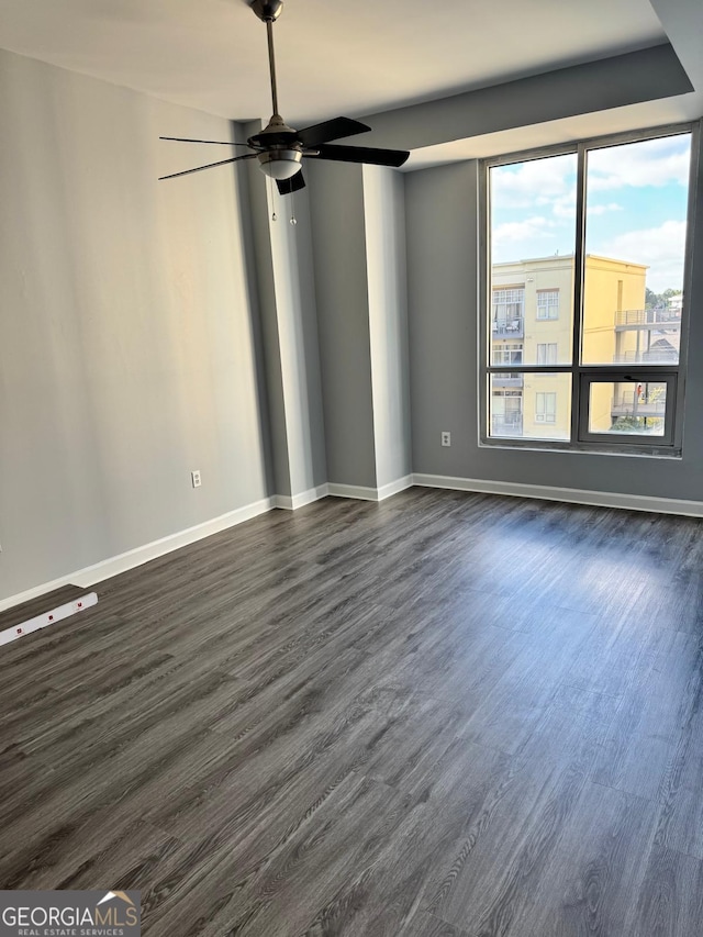 spare room featuring baseboards, dark wood-type flooring, and ceiling fan