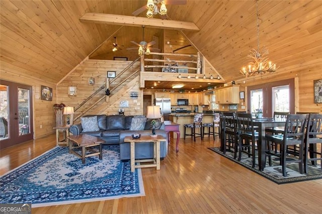 living room featuring wooden walls, beam ceiling, hardwood / wood-style flooring, wood ceiling, and ceiling fan with notable chandelier