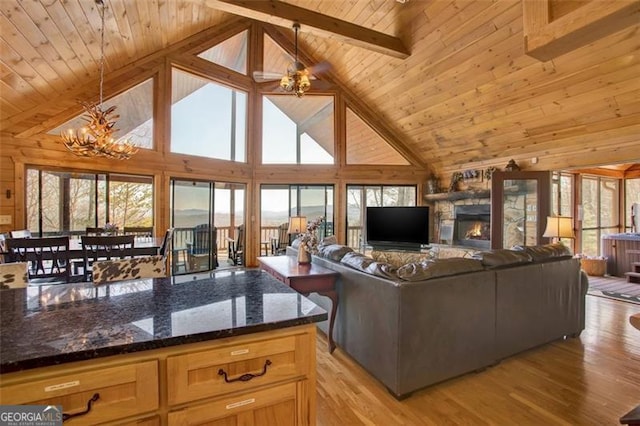 living room featuring light wood-type flooring, beam ceiling, an inviting chandelier, a fireplace, and wood ceiling