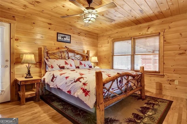 bedroom with wood finished floors, wooden walls, wooden ceiling, and a ceiling fan