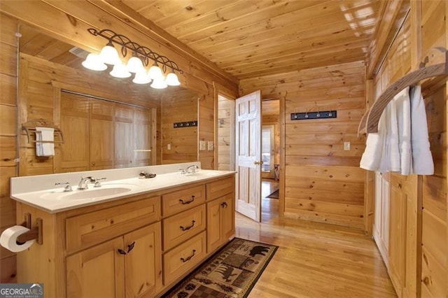 full bath featuring wood finished floors, wood walls, wood ceiling, and a sink