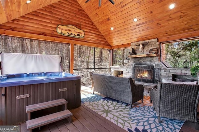 wooden terrace with a gazebo, a hot tub, and an outdoor stone fireplace