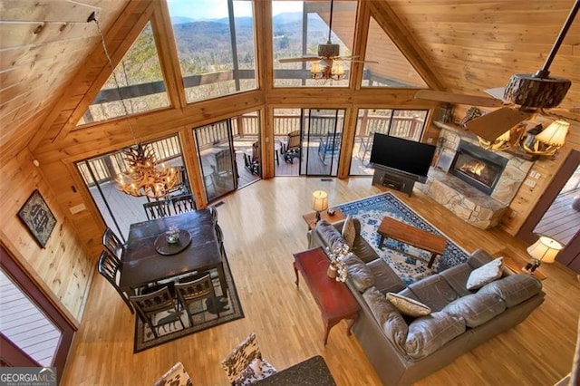 living room featuring wood finished floors, high vaulted ceiling, a fireplace, wood ceiling, and wood walls