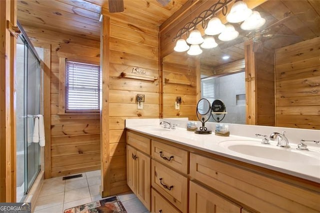 full bath featuring tile patterned flooring, a shower stall, wooden walls, and a sink