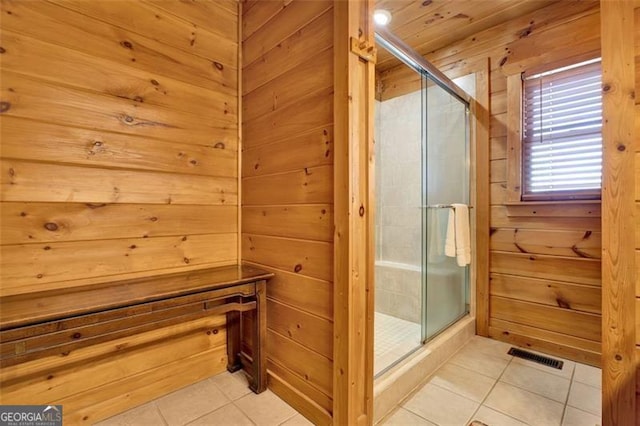 bathroom with tile patterned floors, a stall shower, and wood walls