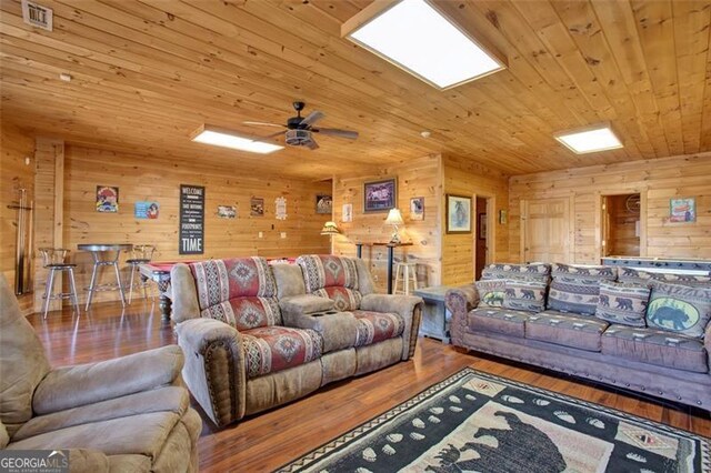 living area with visible vents, ceiling fan, wood walls, wood ceiling, and wood finished floors