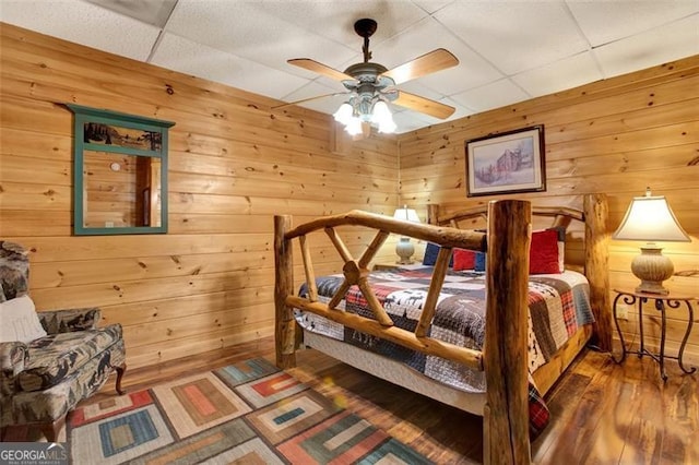 bedroom featuring wood walls, a paneled ceiling, and wood finished floors