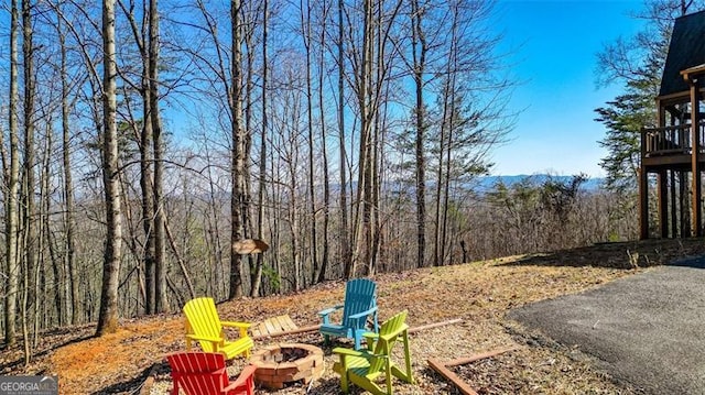 view of yard featuring a forest view and a fire pit