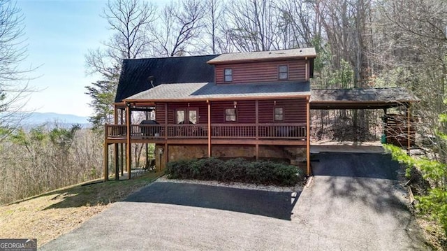 log cabin with faux log siding, aphalt driveway, and a carport