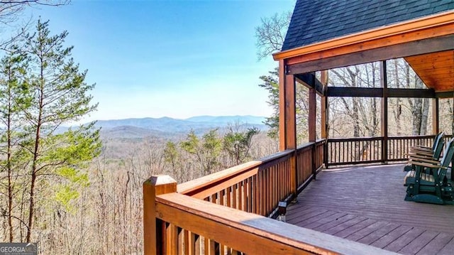 wooden terrace featuring a view of trees and a mountain view