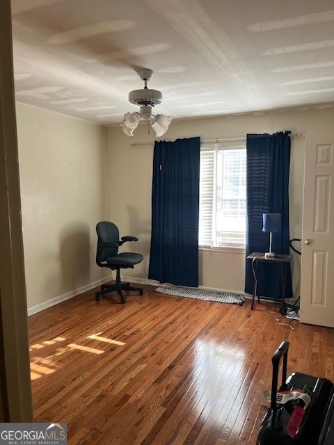 interior space with baseboards, hardwood / wood-style floors, and a ceiling fan