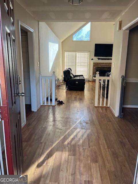 interior space with a fireplace, lofted ceiling with beams, baseboards, and wood finished floors