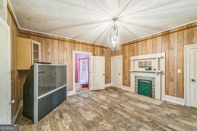 unfurnished living room with wood walls, a tile fireplace, an inviting chandelier, and wood finished floors