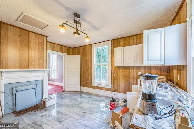 kitchen featuring wooden walls, a fireplace, white cabinetry, and baseboards