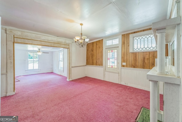 interior space featuring ornamental molding, ceiling fan with notable chandelier, and carpet floors