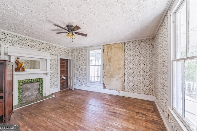 unfurnished living room featuring wallpapered walls, ceiling fan, wood finished floors, and ornamental molding