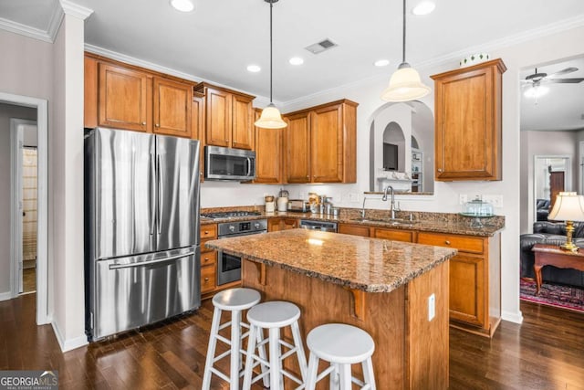 kitchen with visible vents, dark stone counters, brown cabinetry, stainless steel appliances, and a sink