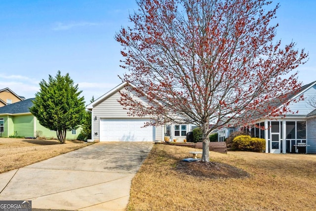 obstructed view of property featuring a front yard, concrete driveway, an attached garage, and a sunroom