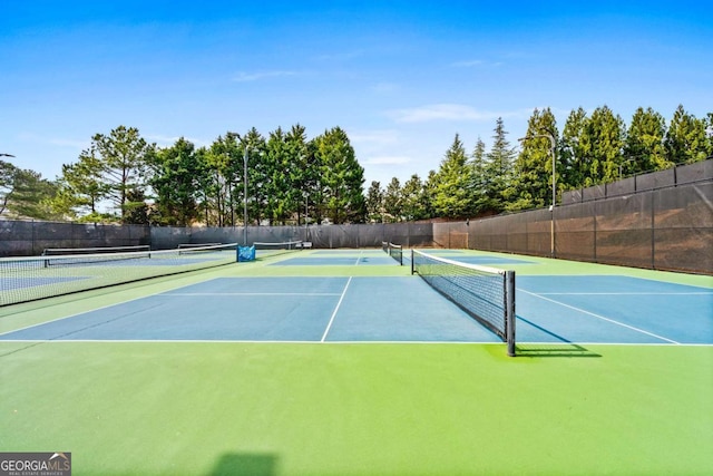 view of tennis court with community basketball court and fence