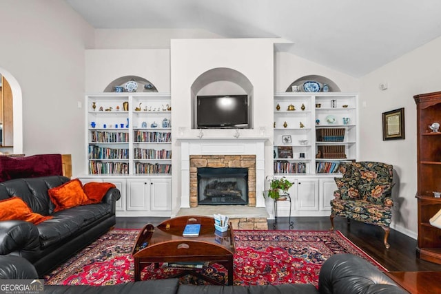 living area with built in shelves, wood finished floors, arched walkways, a fireplace, and lofted ceiling