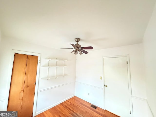 spare room with visible vents, wood finished floors, and a ceiling fan