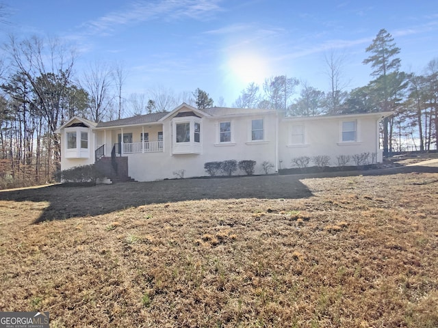 view of front of property with covered porch, stucco siding, and a front yard