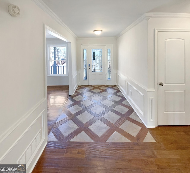 foyer with visible vents, a wainscoted wall, light wood-style floors, crown molding, and a decorative wall