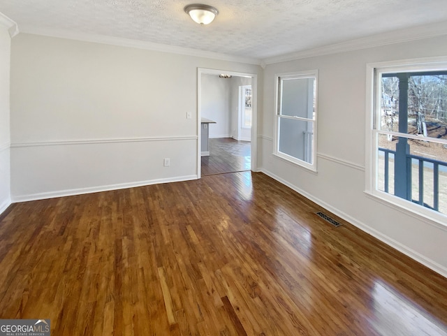 unfurnished room featuring visible vents, ornamental molding, a textured ceiling, dark wood-style floors, and baseboards