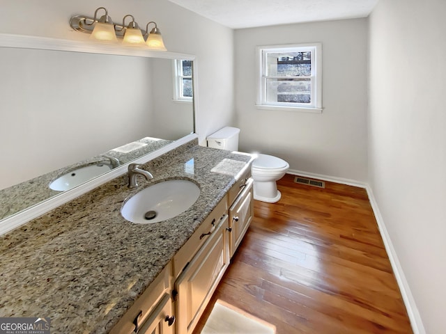 bathroom with visible vents, toilet, hardwood / wood-style floors, baseboards, and vanity